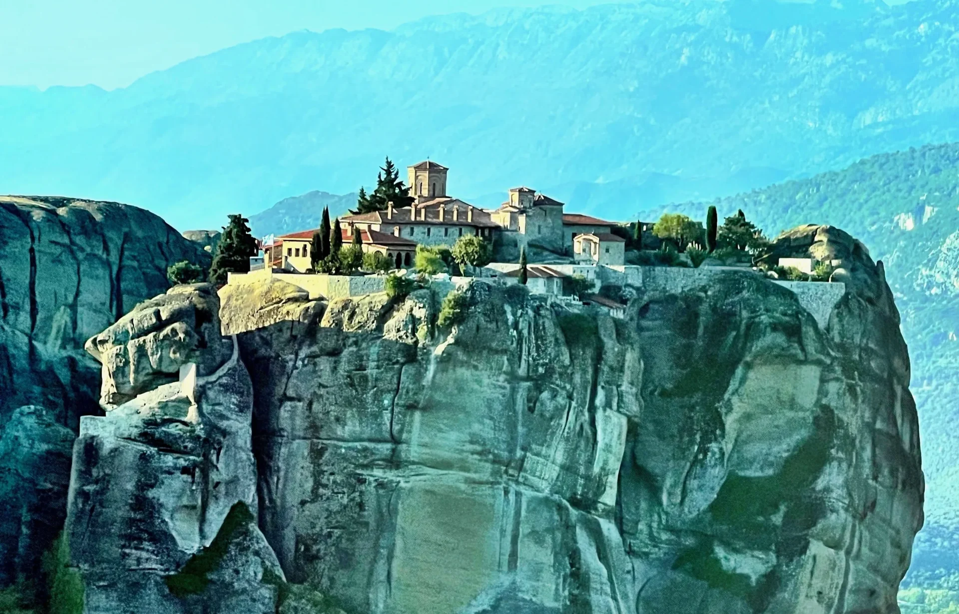 A painting of the monastery on top of a cliff.